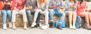 a group of people sitting on a wall while looking at their phones