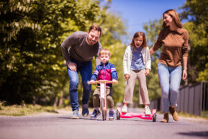 family on a street with kids on hoverboard and scooter