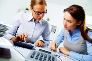two women looking at numbers and using calculators