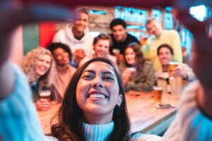 young woman taking selfie of herself with group