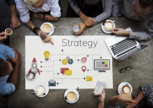 people sitting at a table drinking coffee while looking at a diagram of strategy