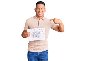 young handsome latin man holding scribble draw pointing finger to himself